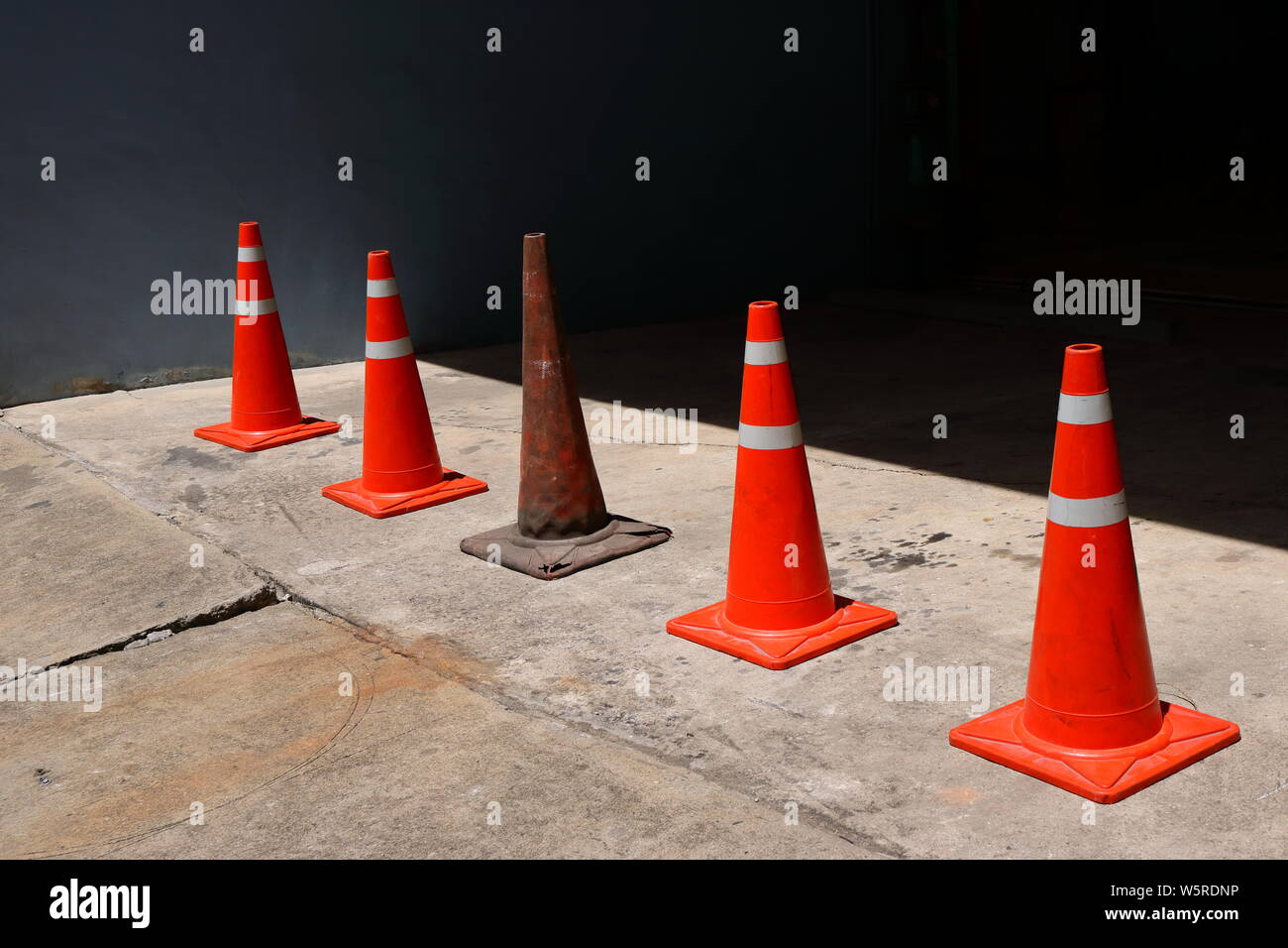 Closeup of an old traffic cone among the new ones, dare to be different concept Stock Photo