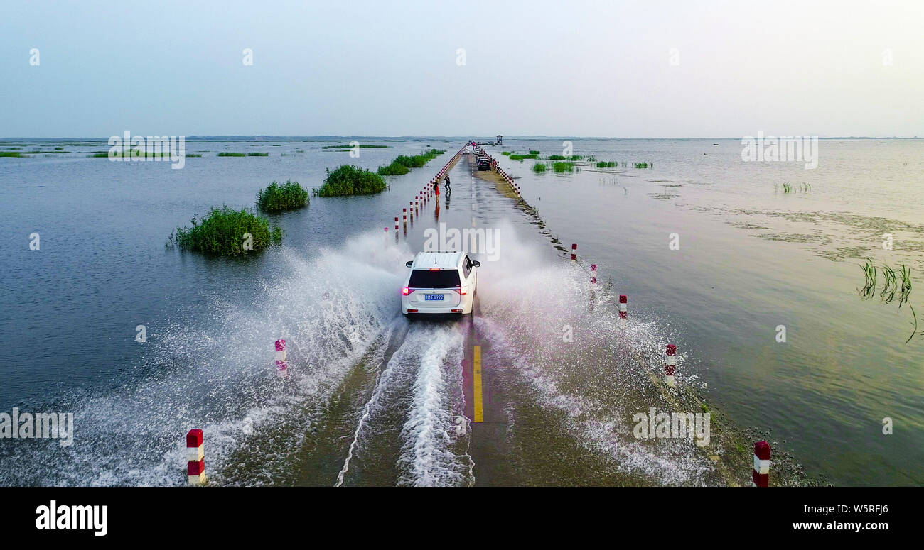 Cars drive on the Yongwu Road submerged in rising water of the Poyang Lake due to heavy rainfall in Jiujiang city, east China's Jiangxi province, 23 J Stock Photo