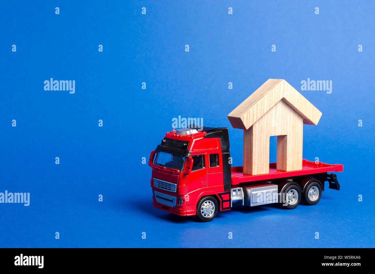 A red truck transports a wooden house. Concept of transportation and cargo shipping, moving company. Construction of new houses and objects. Industry. Stock Photo