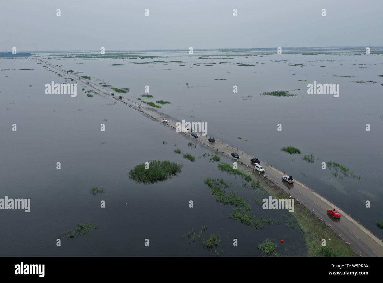 Cars drive on the Yongwu Road submerged in rising water of the Poyang Lake due to heavy rainfall in Jiujiang city, east China's Jiangxi province, 24 J Stock Photo