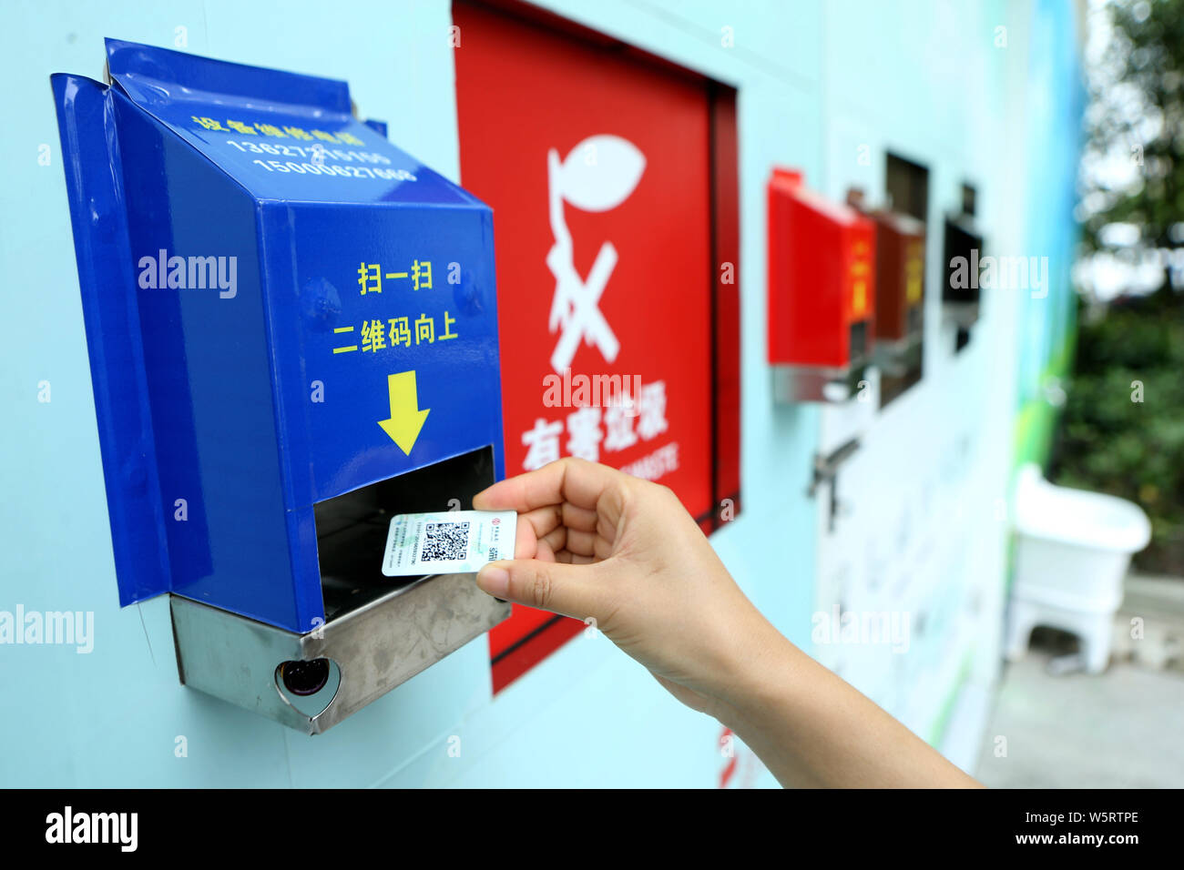 Local residents use QR code cards to open different bins to put their garbage at a waste