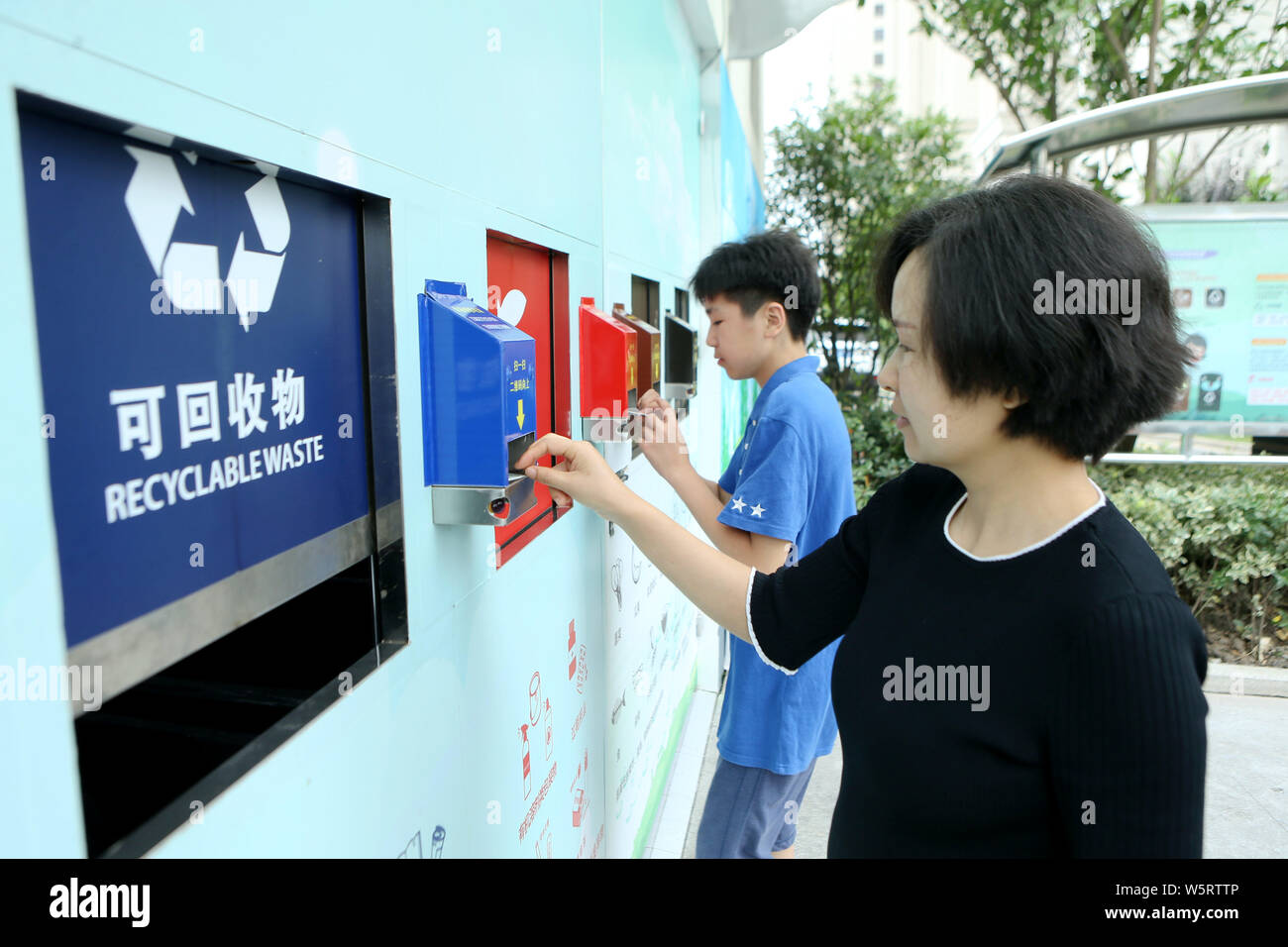 Local residents use QR code cards to open different bins to put their garbage at a waste