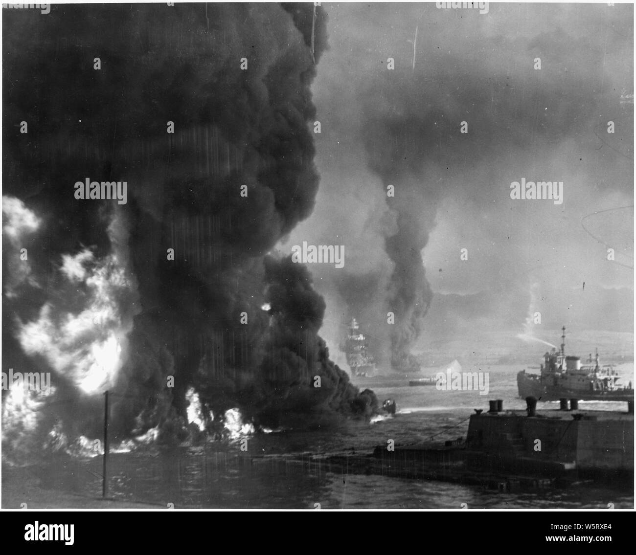 Naval photograph documenting the Japanese attack on Pearl Harbor, Hawaii which initiated US participation in World War II. Navy's caption: Oil burning on top of the water near the Naval Air Station at Pearl Harbor after the Japanese attack on Dec. 7, 1941.; Scope and content:  This photograph was originally taken by a Naval photographer immediately after the Japanese attack on Pearl Harbor, but came to be filed in a writ of application for habeas corpus case (number 298) tried in the US District Court, District of Hawaii in 1944. The case, In Re Lloyd C. Duncan related to imposition of martial Stock Photo