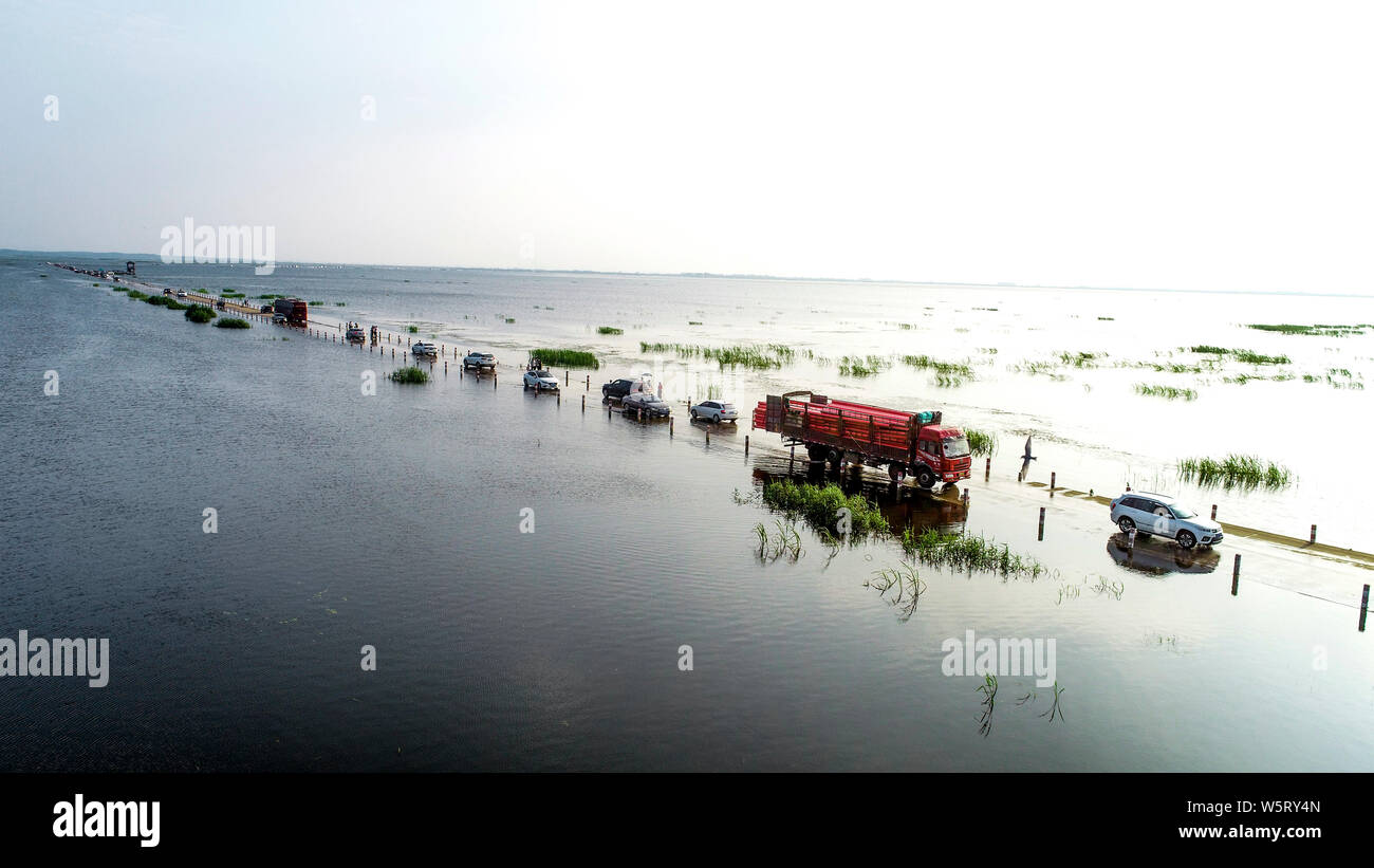 Cars drive on the Yongwu Road submerged in rising water of the Poyang Lake due to heavy rainfall in Jiujiang city, east China's Jiangxi province, 23 J Stock Photo