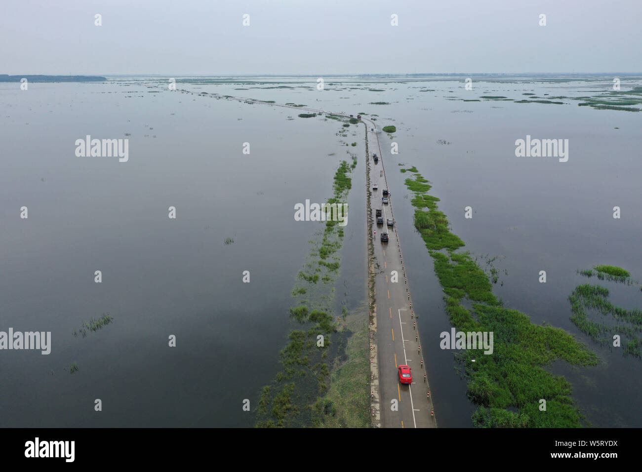 Cars drive on the Yongwu Road submerged in rising water of the Poyang Lake due to heavy rainfall in Jiujiang city, east China's Jiangxi province, 24 J Stock Photo
