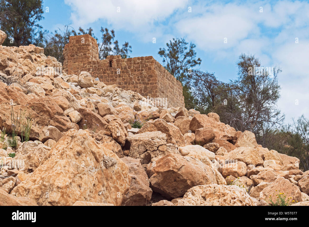 low angle of the stone mamluk era flour mill at ein gedi spring in israel with a rocky hillside in the foreground and cloudy sky in the background Stock Photo