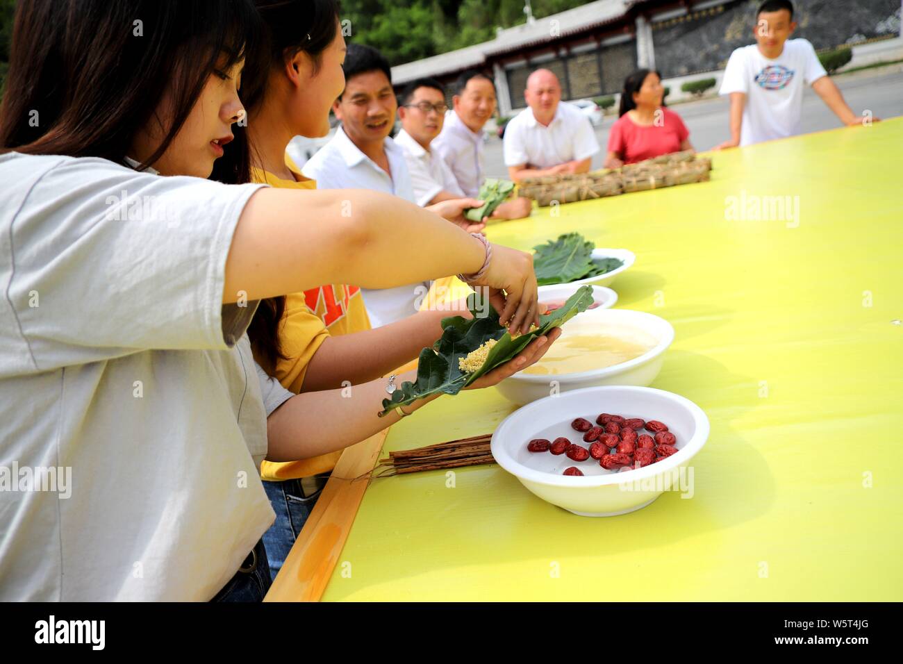 Local residents make Zongzi, a kind of large glutinous rice dumplings, featuring shape of 'flying dragon', ahead of the Chinese Dragon Boat Festival o Stock Photo