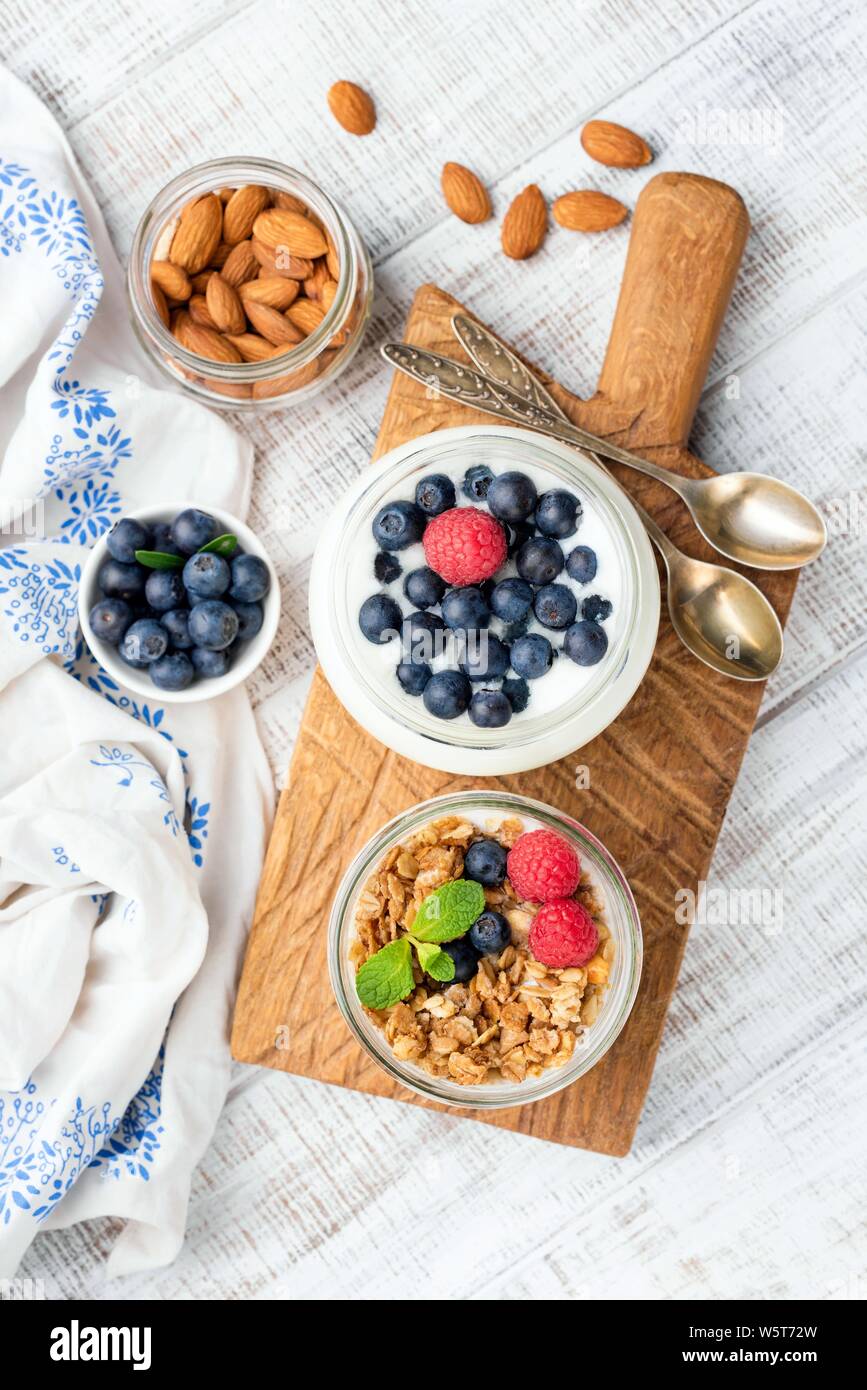 Yogurt with blueberries and granola in jar on wooden serving board. Top view. Clean eating, dieting, weight loss concept. Healthy food Stock Photo