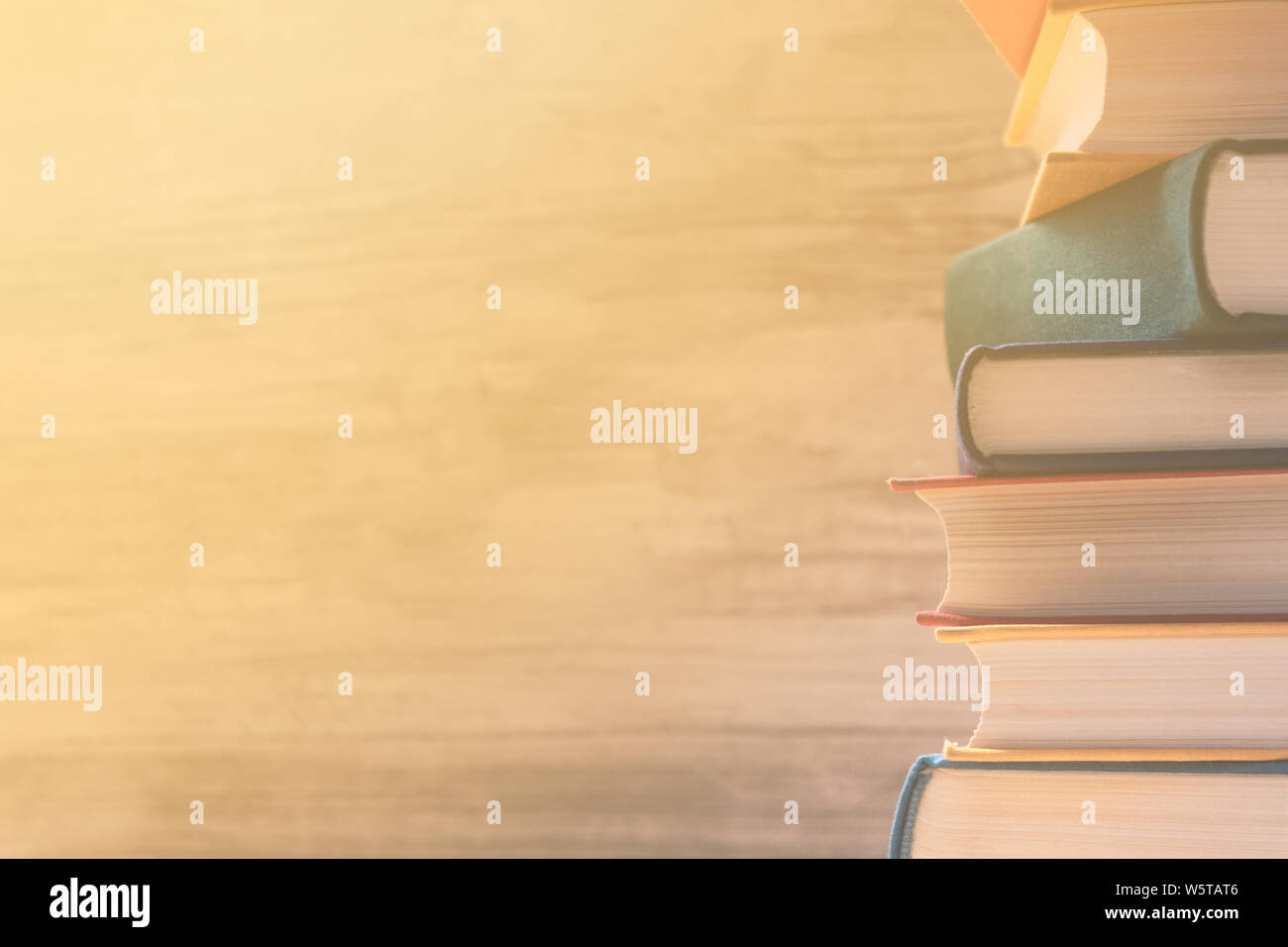 Stack of colorful pastel books on a shelf in the library. Sun's rays fall on the books through the window. Education concept. Back to school  backgrou Stock Photo