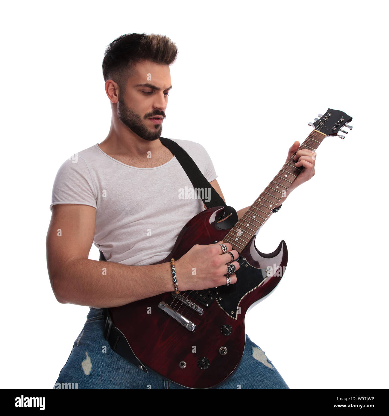 portrait of casual man strumming his electric guitar while standing on