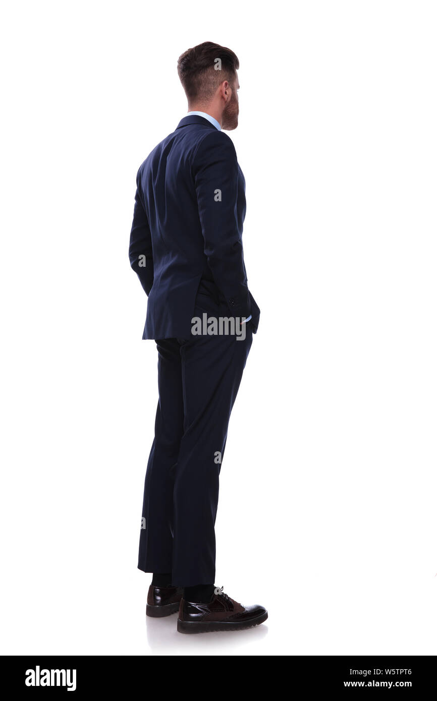 turned businessman in navy suit looks to side while standing on white ...