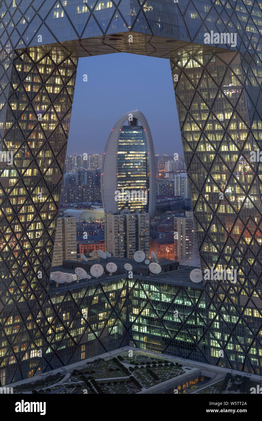 A night view of the new headquarters building of the People's Daily seen through the new CCTV Tower in the Central Business District (CBD) in Beijing, Stock Photo