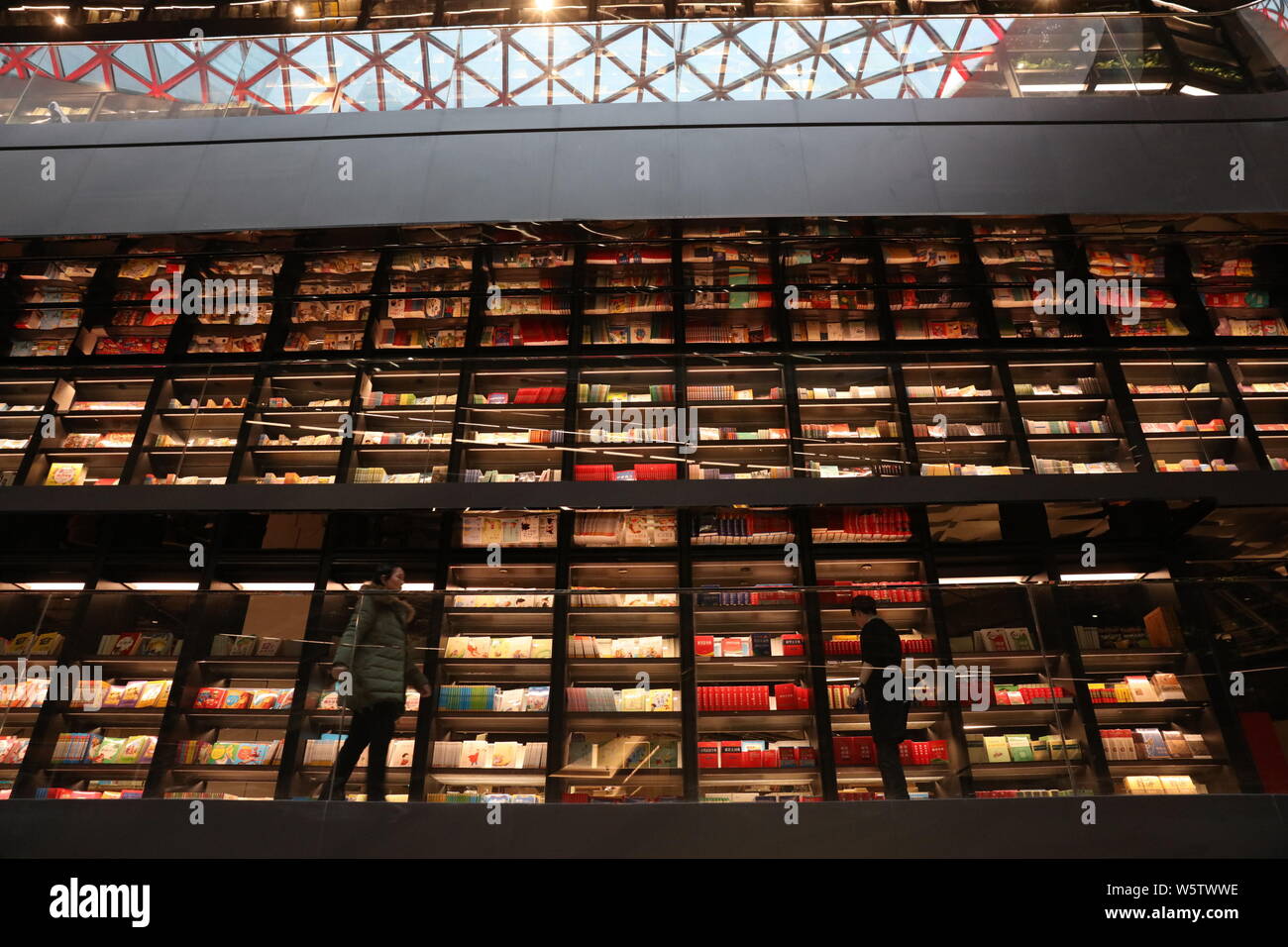 Books are placed on the four-storey-high book wall decorated with glass with a height of 18 meters at a shopping mall in Xi'an city, northwest China's Stock Photo