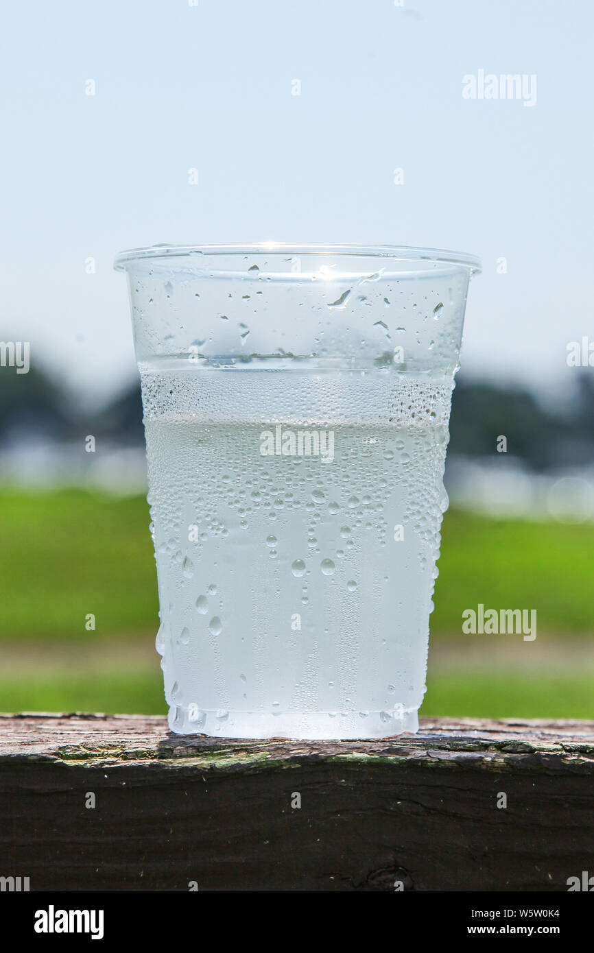 Plastic cup half full of water to show the ice melted Stock Photo