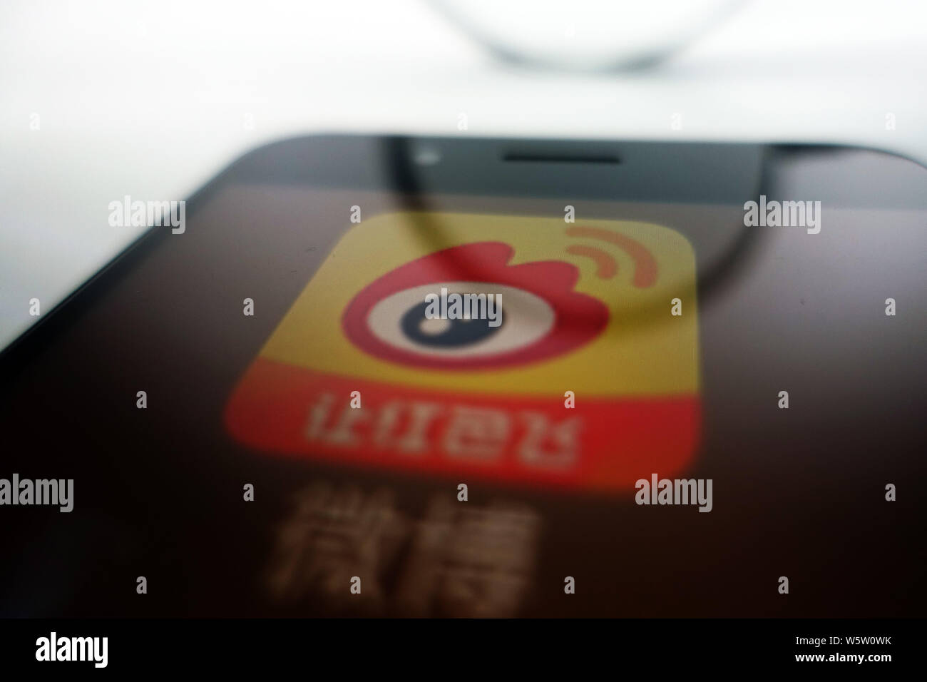 --FILE--A Chinese netizen looks at a logo of Weibo, the Twitter-like microblogging service of Chinese Internet portal Sina, on his smartphone in Ji'na Stock Photo