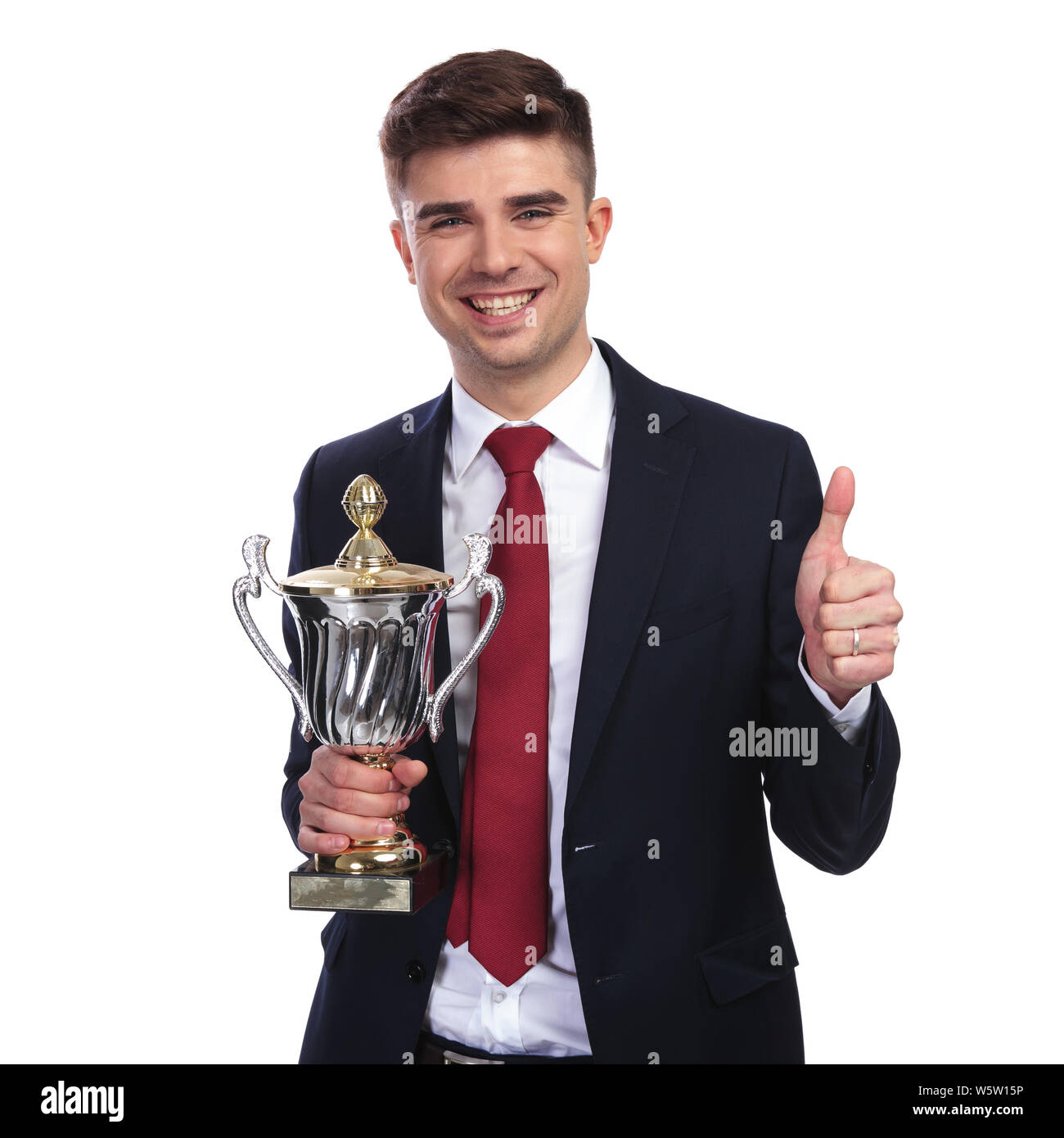 portrait of young businessman holding trophy and making ok sign while ...