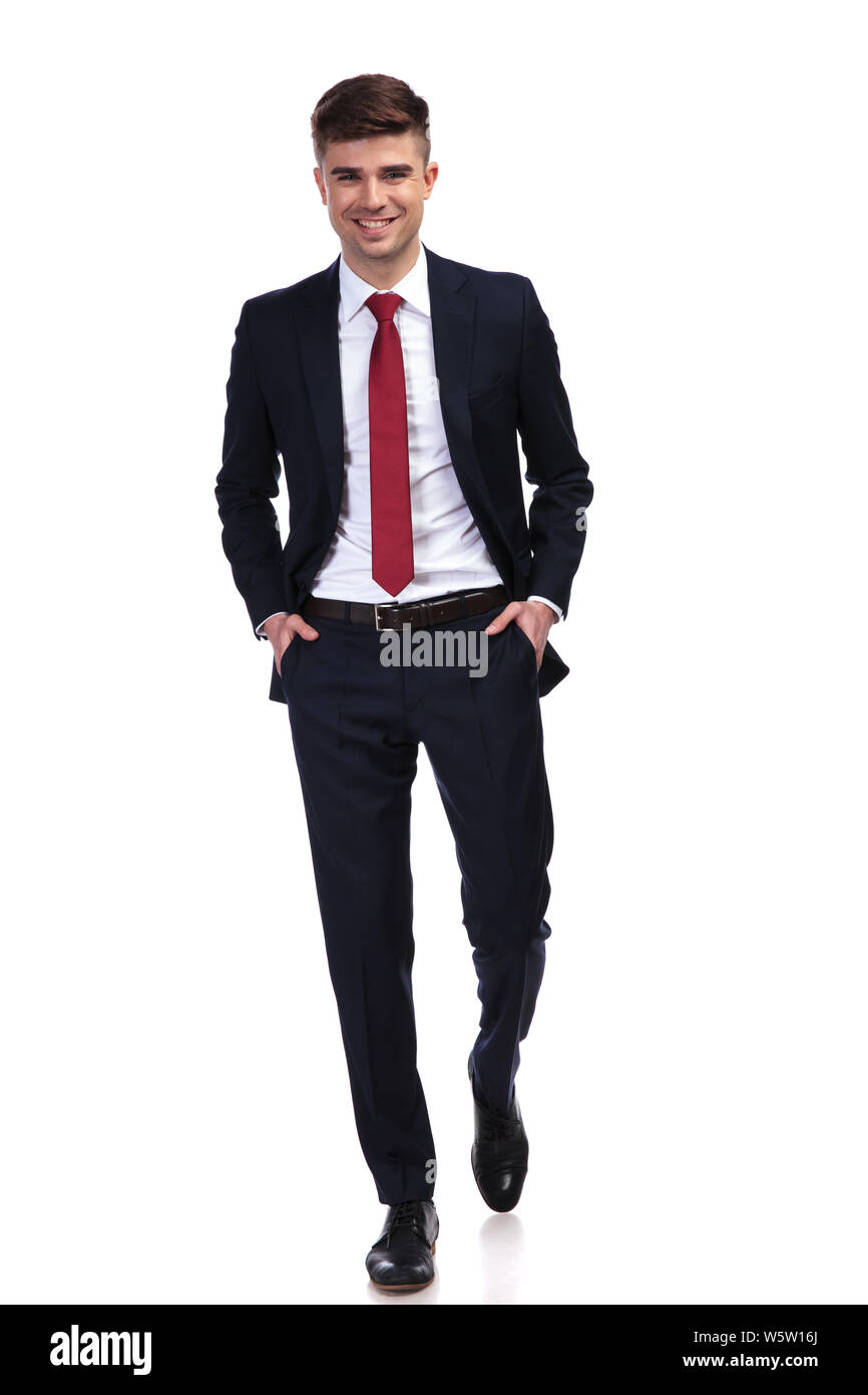 mulighed Foresee Oh happy relaxed businessman wearing a navy suit and a red tie, walking with  hands in pockets and smiling while standing on white background, full body  p Stock Photo - Alamy