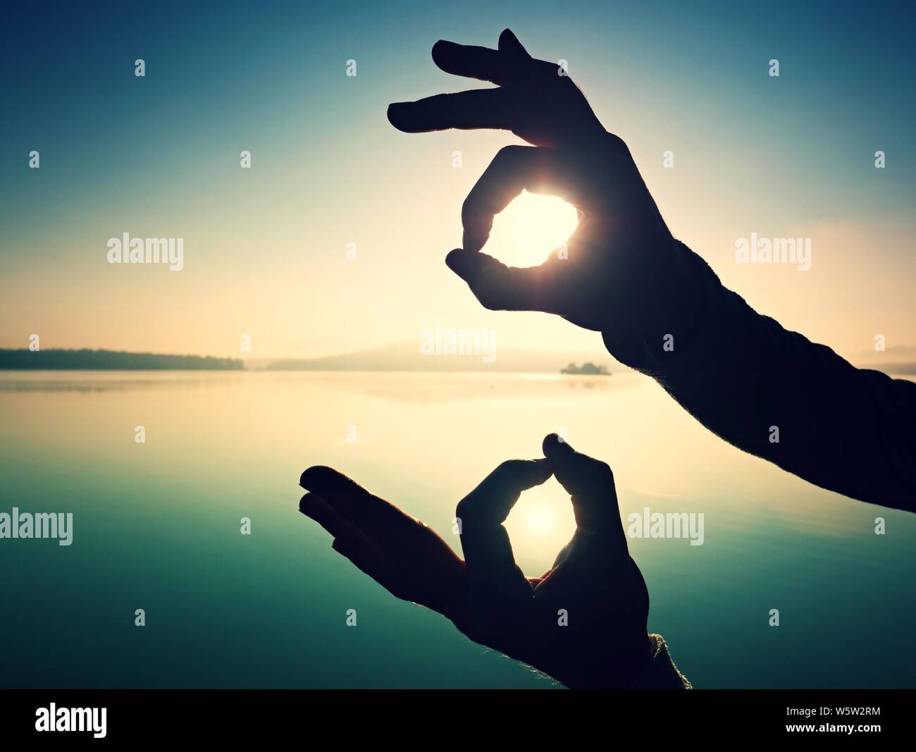 Hand touch Sun. Palm shadow play with rising sun above lake and sun ...