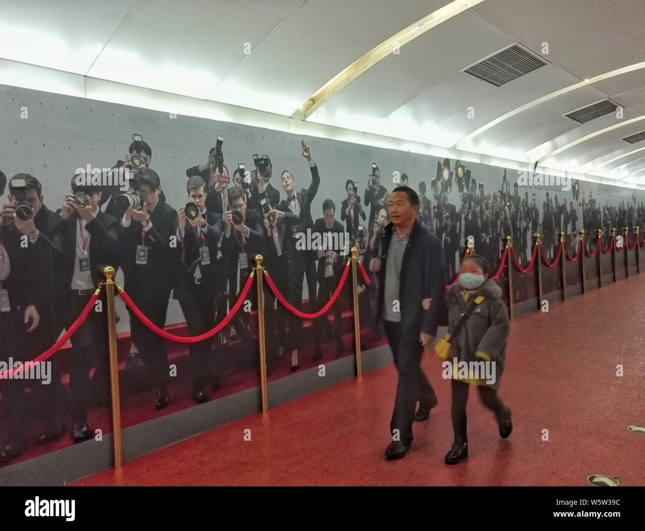 Passengers walk past a 60-meter-long mural of paparazzi at a red carpet event made by Chinese personalized news app Toutiao.com of Bytedance Ltd. at t Stock Photo