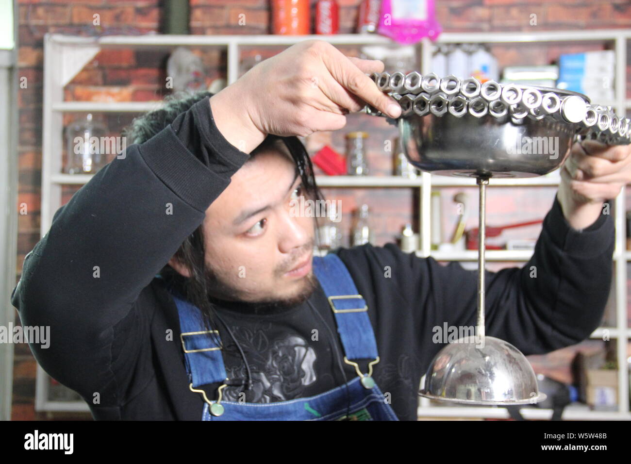 Chinese craftsman Geng Shuai uses bolts and nuts to make an artwork at ...