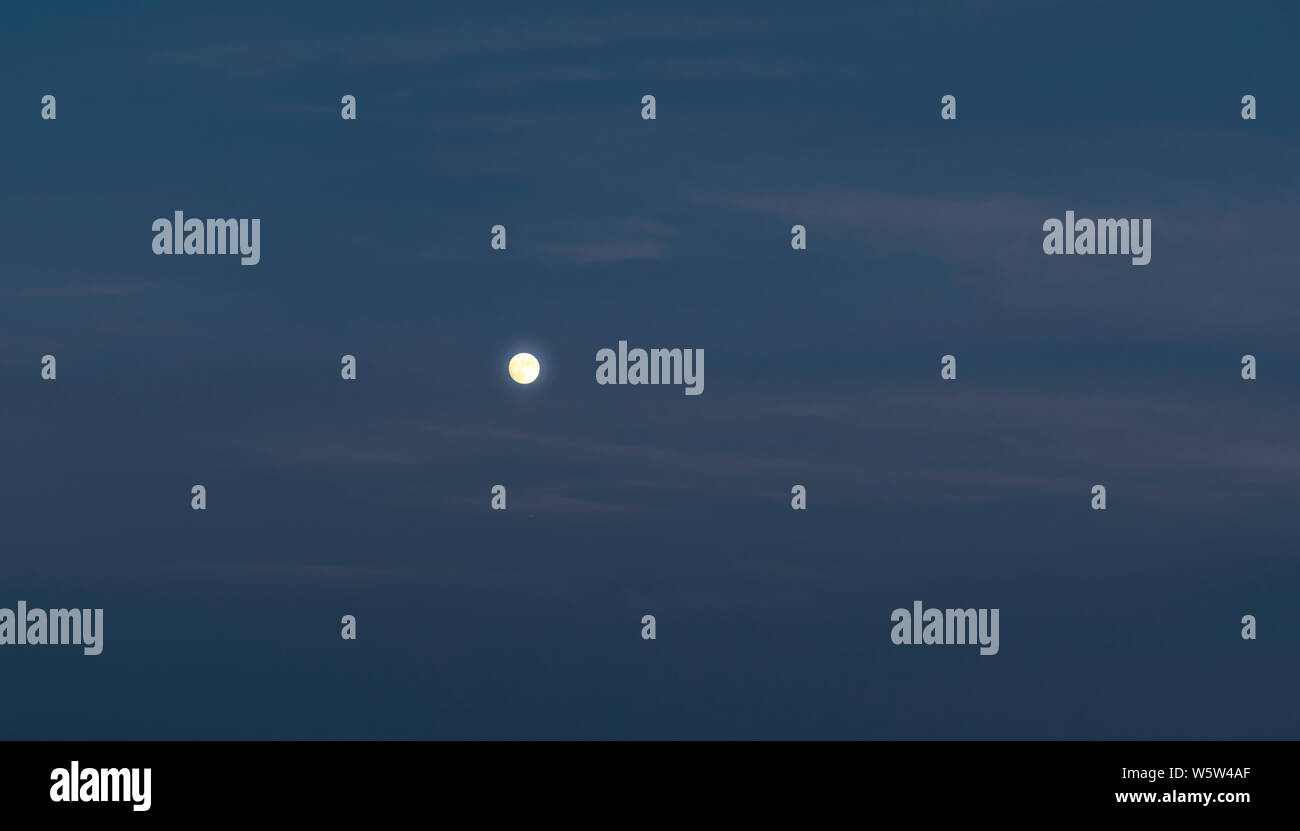 Moon in the evening sky during blue hour. Stock Photo