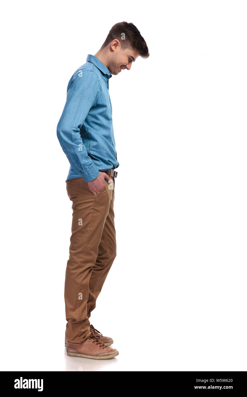 side view of a smiling casual man looking down at something on white background Stock Photo