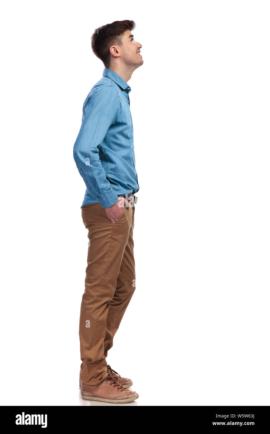 side view of a casual man looking up at something while standing with hands  in pockets on white background Stock Photo - Alamy