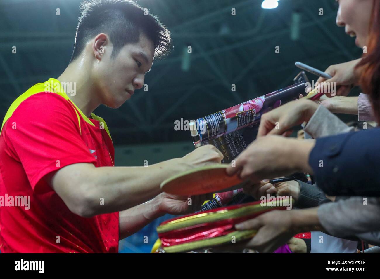 Fan Zhendong of China signs autographs for fans after defeating Koki Niwa of Japan in their men's singles Round of 16 match during the Seamaster 2018 Stock Photo