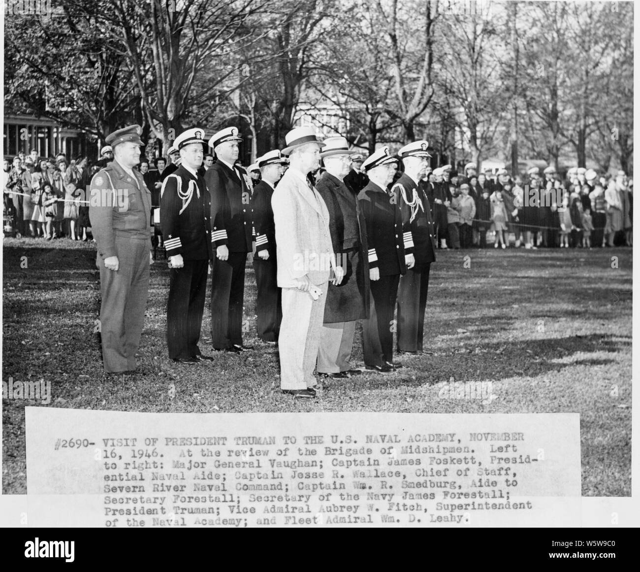Photograph of President Truman watching the Brigade of Midshipmen pass in review, during his visit to the U.S. Naval Academy: (left to right) General Harry Vaughan, Military Aide to the President; Captain James Foskett, Naval Aide to the President; Captain Jesse R. Wallace, Chief of Staff, Severn River Naval Command; Captain W. R. Smedburg, aide to Secretary Forrestal; Secretary of the Navy James Forrestal; the President; Vice Admiral Aubrey Fitch, Superintendent of the Naval Academy; and Fleet Admiral William D. Leahy. Stock Photo