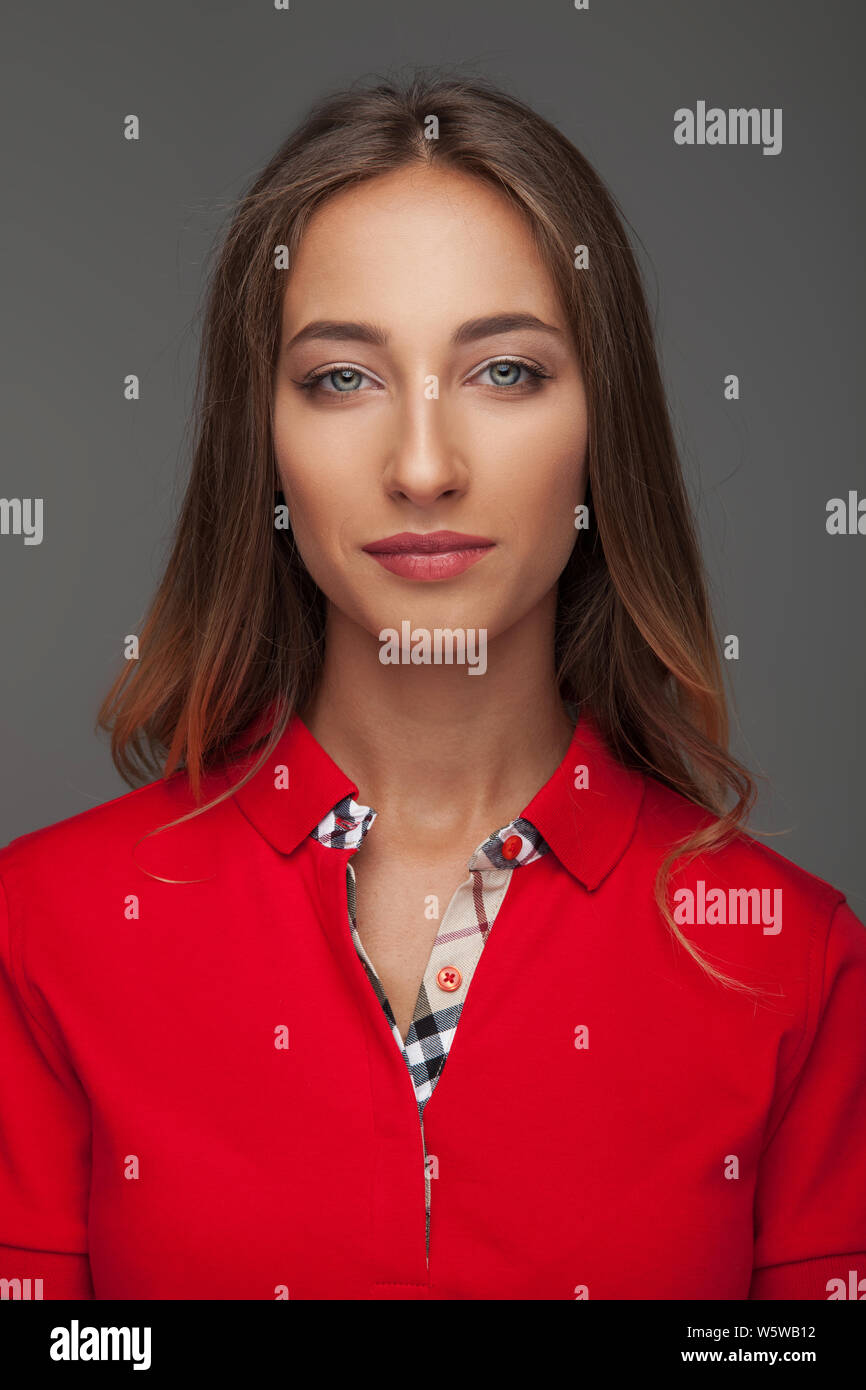 portrait of an attractive woman in red polo shirt on grey backgrouond Stock Photo