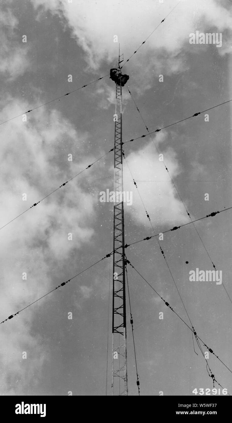 Photograph of Tower Men Installing and Adjusting J Type Antenna; Scope and content:  Original caption: The tower men remain aloft for 2 hours, installing & adjusting J type VHF antenna on top of mast at Baldwin Ranger Station. The J type antenna will be replaced by a type P.D.V.H.F. antenna for improved radiation characteristics in horizontal plane. Lo. Stock Photo