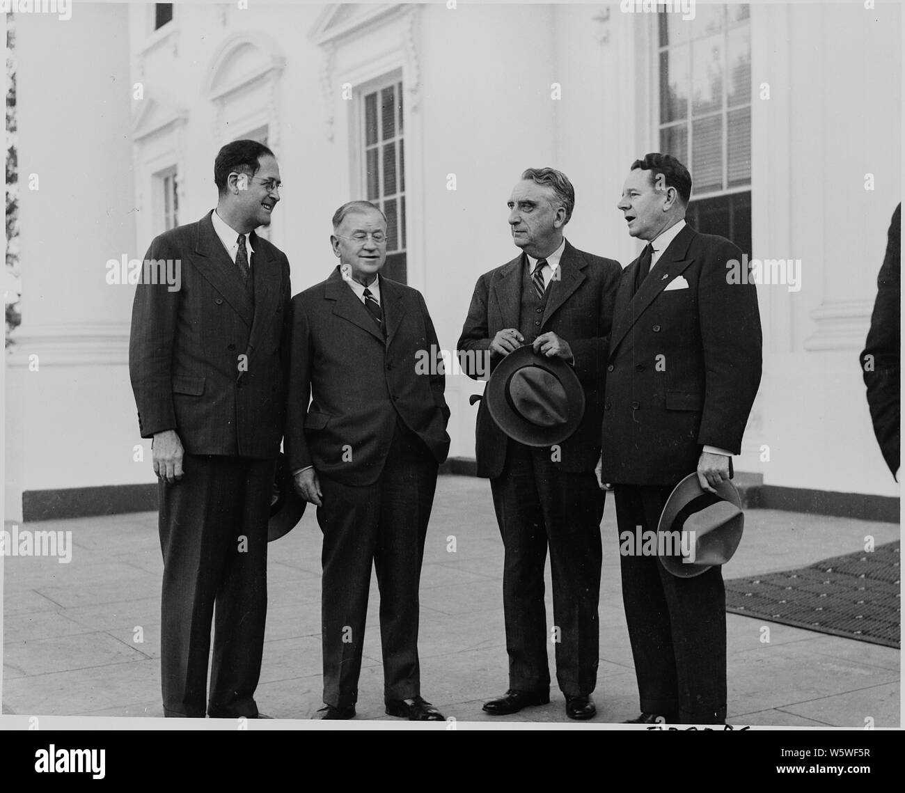 Photograph of Truman administration officials outside the White House, evidently on occasion of welcoming ceremonies for President Juan Antonio Rios of Chile: (from left to right) Secretary of Agriculture Clinton Anderson; Secretary of the Interior Harold Ickes; Secretary of the Treasury Fred Vinson; and (probably) John Blandford, Jr. of the National Housing Agency. Stock Photo