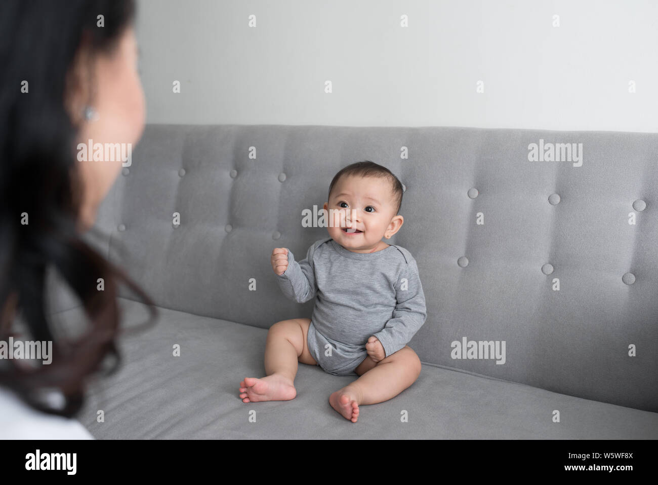 Young mother with her one years old little son dressed in pajamas are relaxing and playing in the living room at the weekend together, lazy morning, w Stock Photo