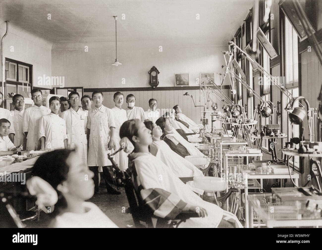 [ 1910s Japan - Japanese Dental Clinic ] —   Students, patients and dental equipment at the student clinic of a Japanese dental school, ca. 1910 (Meiji 43).  20th century vintage gelatin silver print. Stock Photo