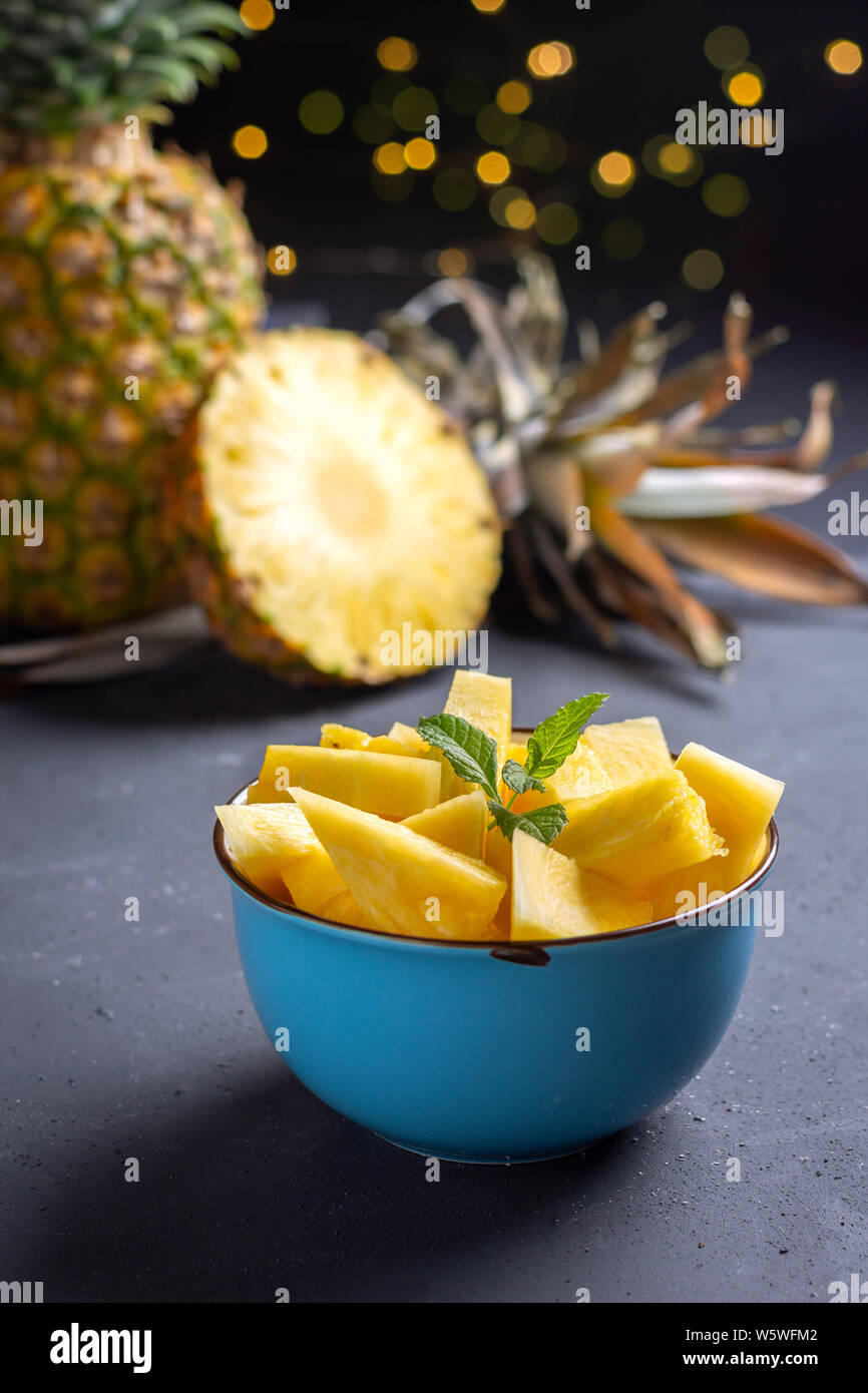 Blue bowl with fresh pineapple on rustic black background Stock Photo