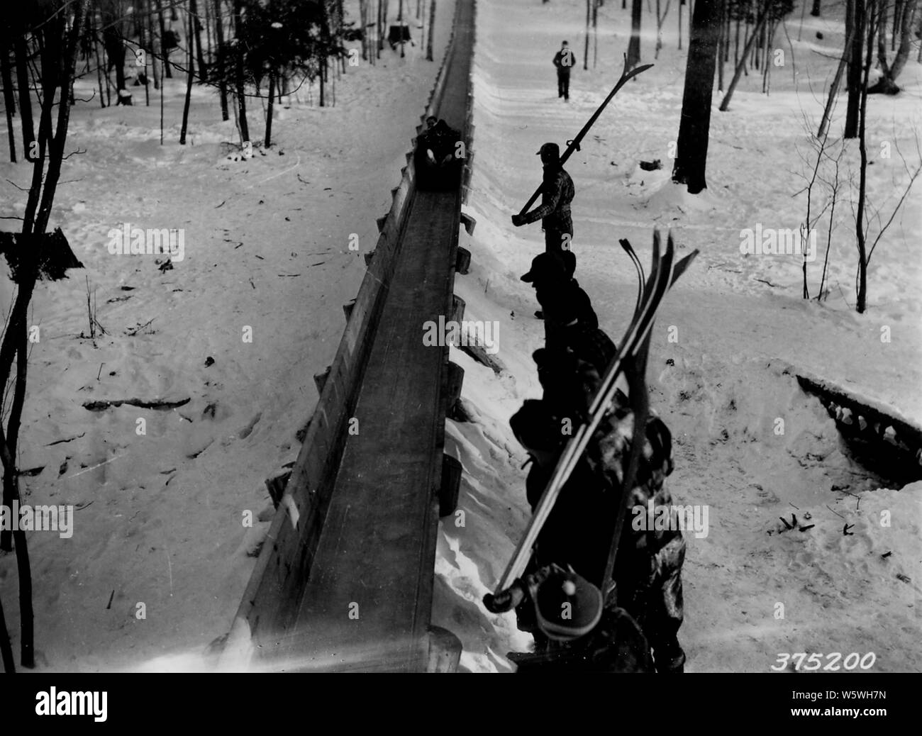 Photograph of a Group of Skiers Watching a Toboggan Coming Down the