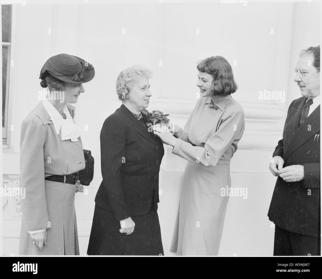 Photograph of actress Ingrid Bergman pinning a corsage on First Lady Bess Truman, who received a community chest award at the White House from a delegation including Miss Bergman, Mrs. Waldron Faulkner, Joseph Steele, and Leigh Ore. Stock Photo