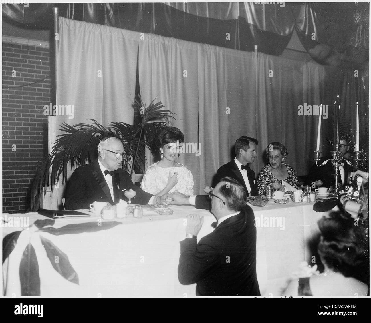 Photograph of former President Harry S. Truman greeting an admirer during an Inaugural Anniversary Dinner at the National Guard Armory in Washington; he is seated beside First Lady Jacqueline Bouvier Kennedy and Attorney General Robert F. Kennedy. Stock Photo