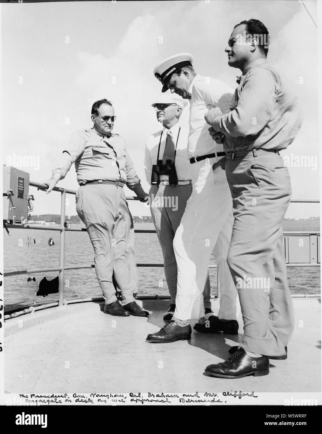 Photograph taken during the vacation cruise of President Harry S. Truman to  Bermuda. On the flying bridge of the yacht Williamsburg, L to R: Gen. Harry  Vaughan, President Truman, Clark Clifford, Gen.