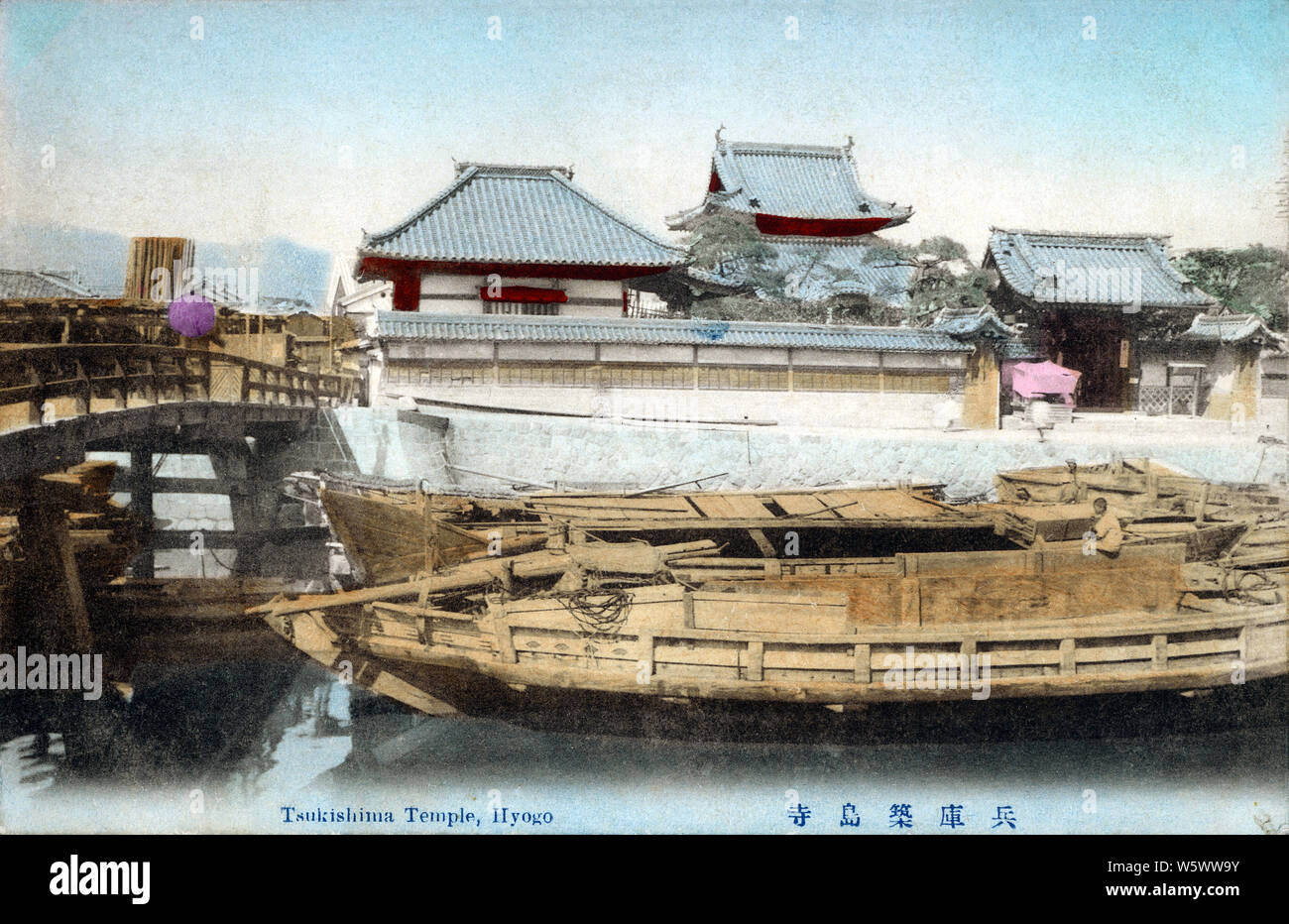 [ 1900s Japan - Japanese Boats and Buddhist Temple ] —   Boats at anchor at Tsukishima Temple (築嶋寺) in Shimagami-cho (島上町) in Hyogo (兵庫), Kobe. Made famous by an ukiyoe print in the Tokaido Meisho No Uchi series ( 東海道名所之内) created by Chikamaru Yukawa (湯川周麿), the temple was destroyed in the Hanshin Awaji Great Earthquake of 1995 (Heisei 7) and rebuilt in concrete. The wooden bridge on this image has been replaced by a huge storm barrier and the temple now has two large concrete buildings on both sides.  20th century vintage postcard. Stock Photo