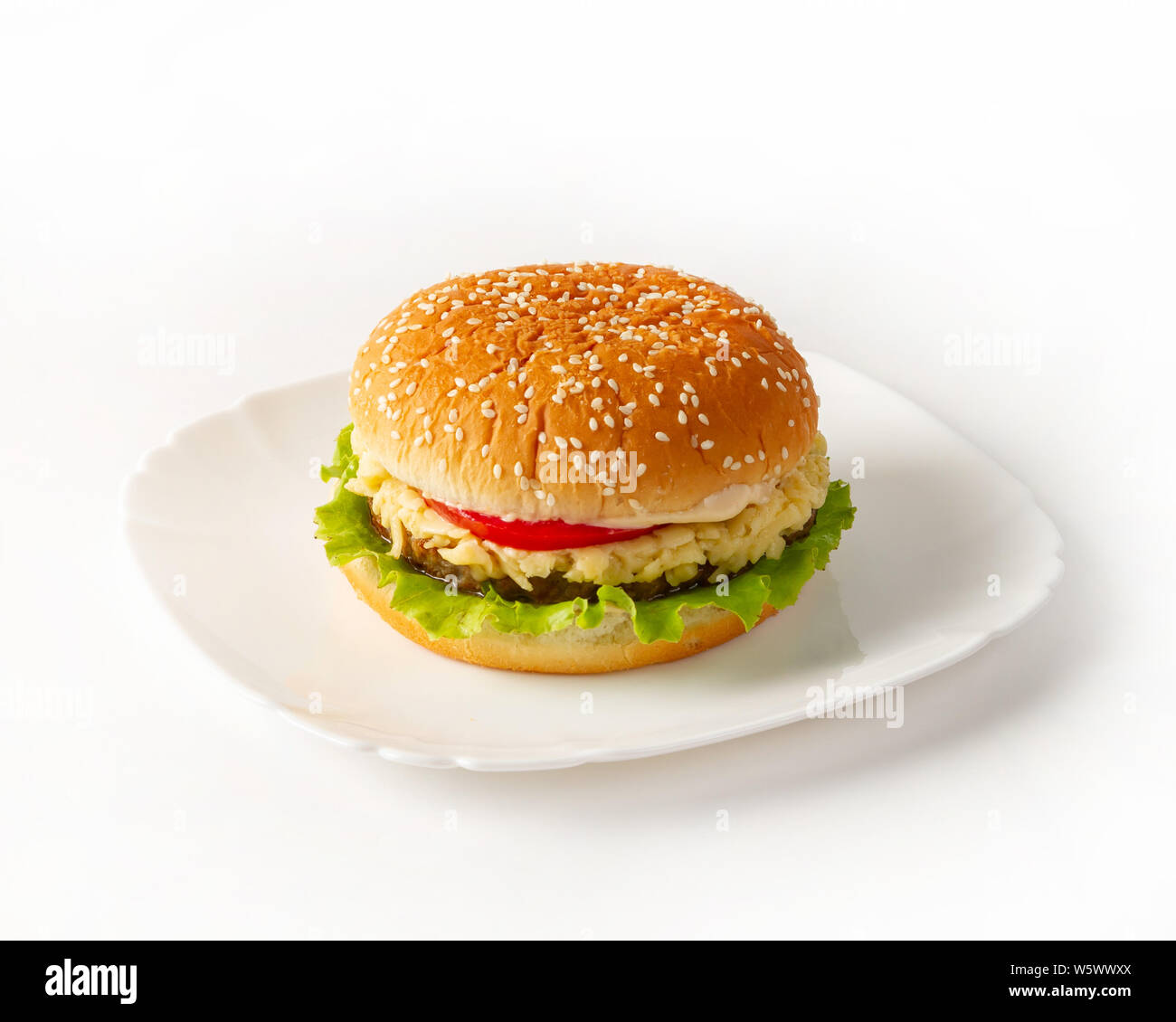 Burger on the plate side view. Lettuce leaves, sesame bun, cheese