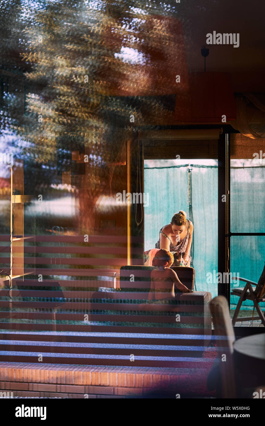 Interior of a house, family spending time at home. Reflections in a glass of window. Candid people, real moments, authentic situations Stock Photo