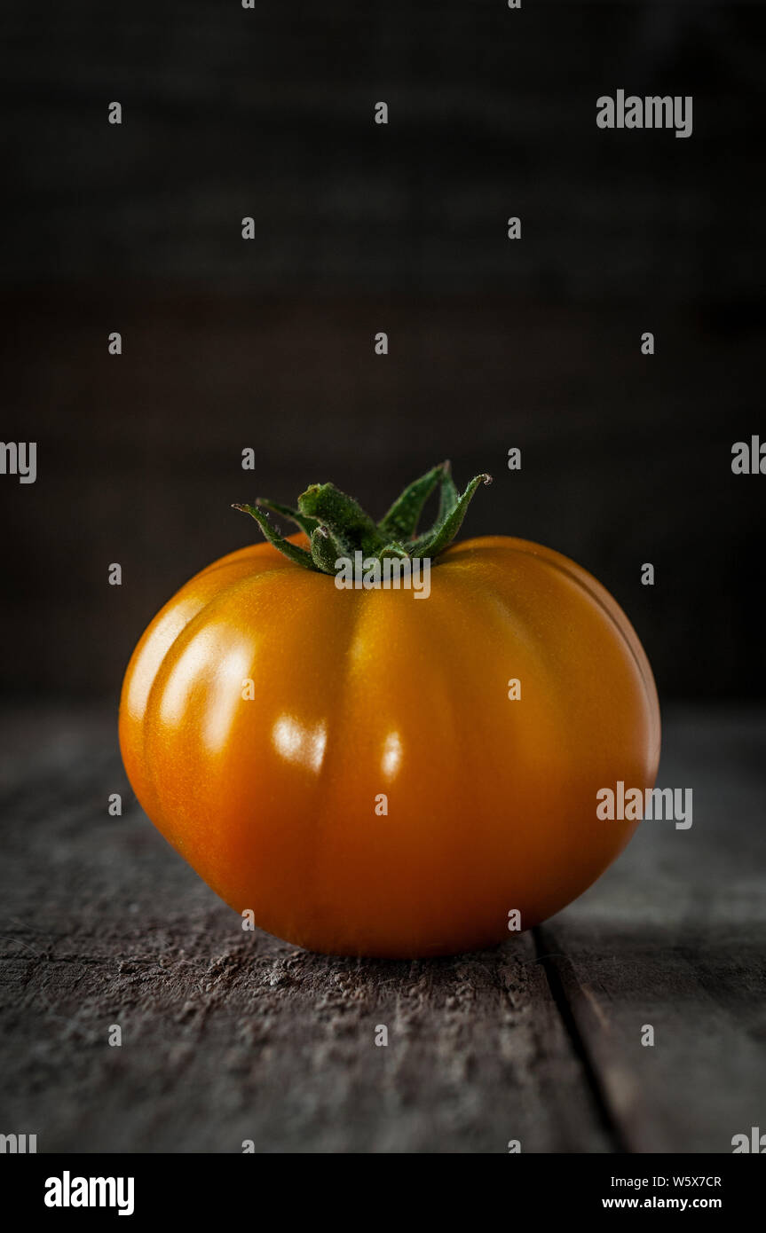 Orange tomato also known as kaki tomato on wooden table Stock Photo