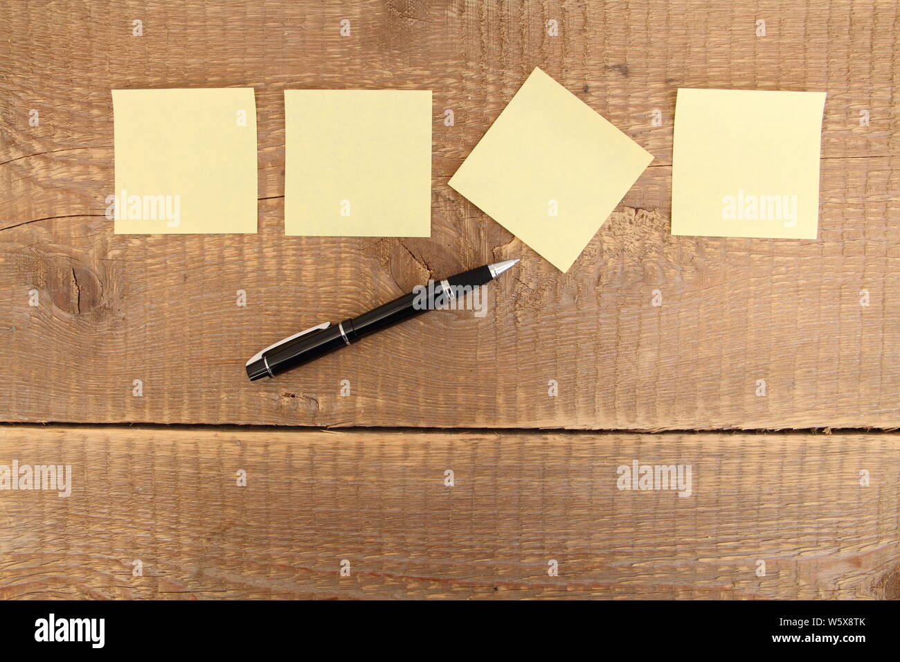 four yellow notes on a wooden table Stock Photo