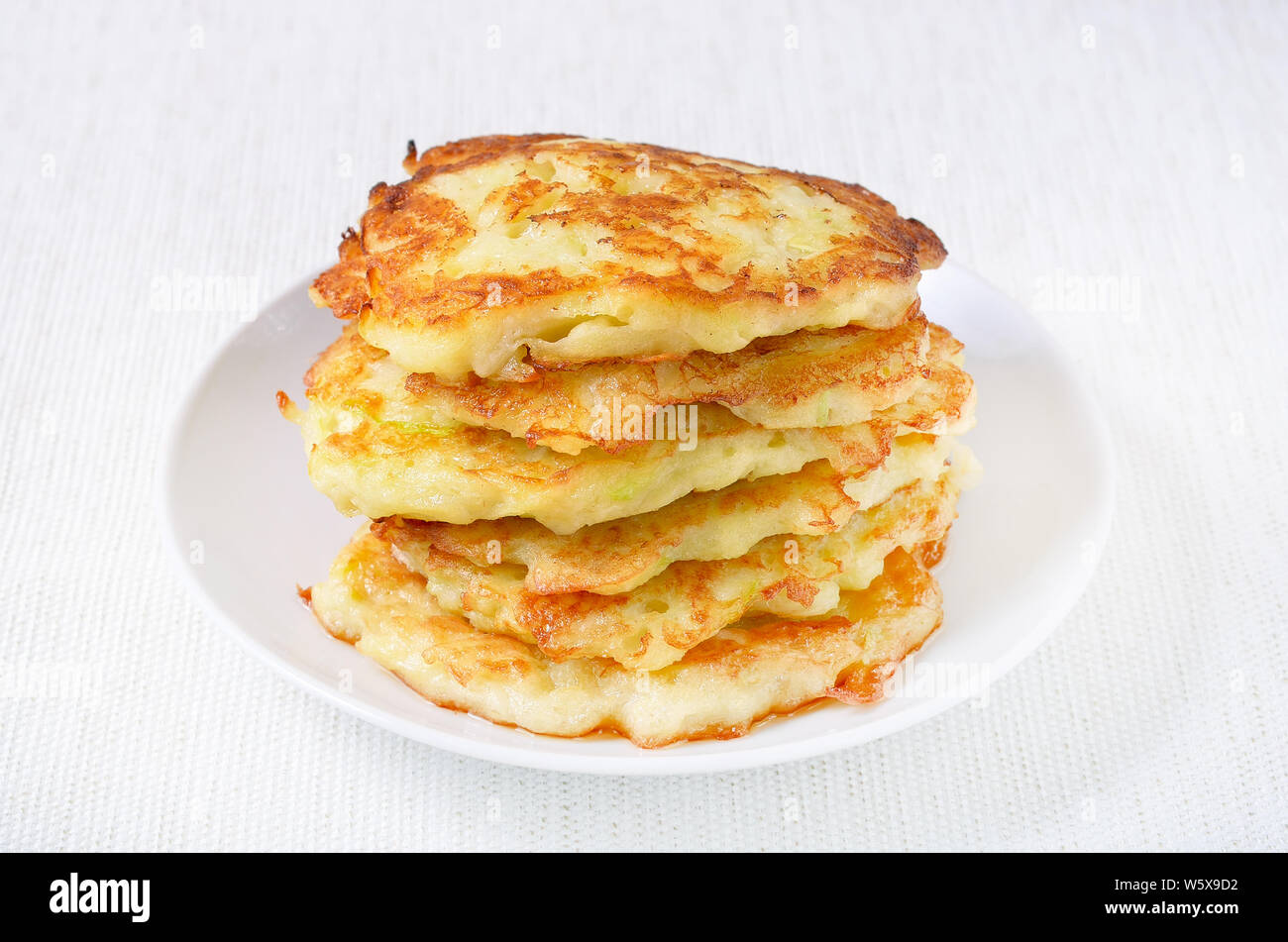Fried courgette pancakes on white plate Stock Photo