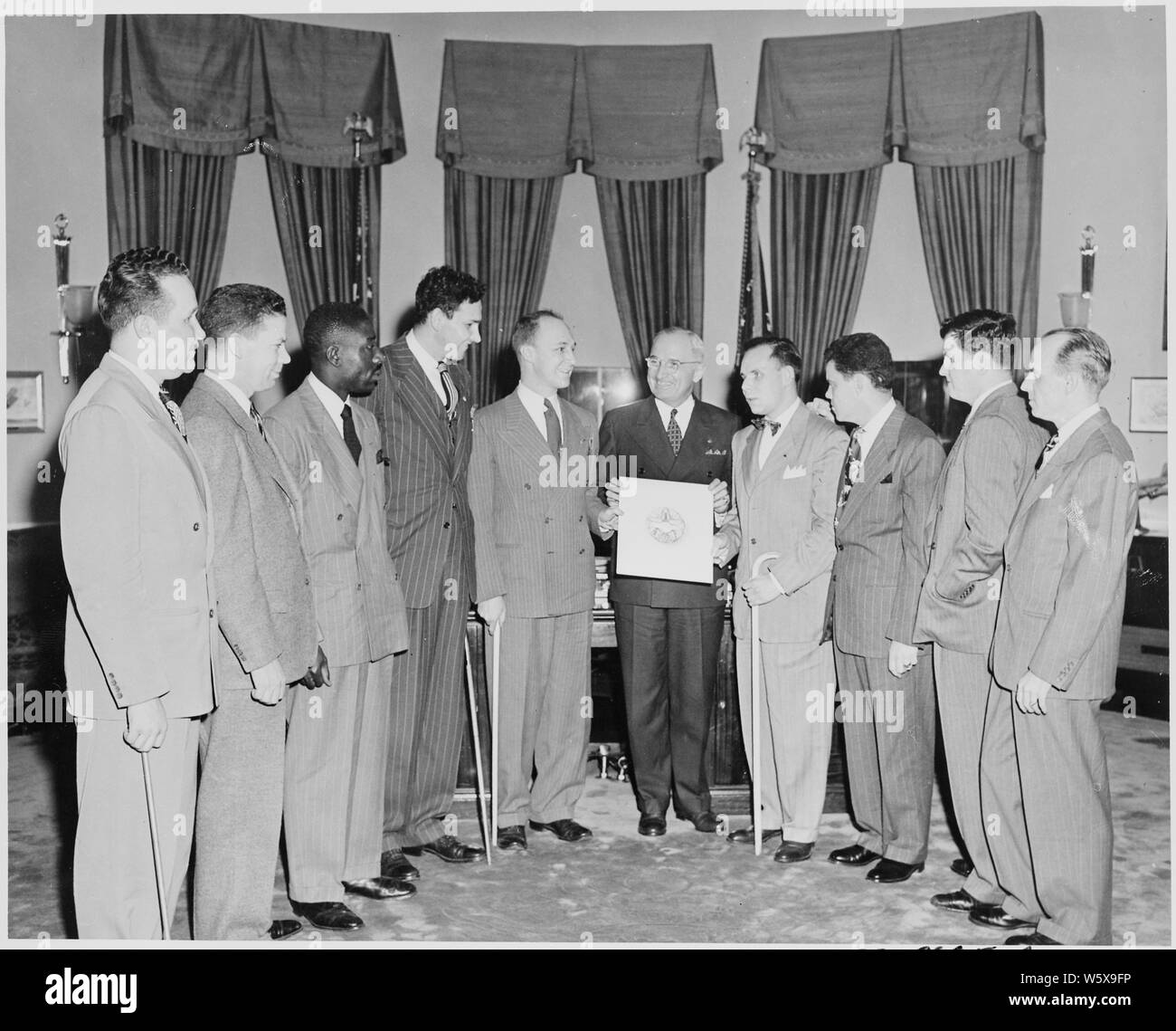 President Truman in the oval office receiving the official insignia of the Blinded Veterans Association. L to R: Lloyd M. Greenwood, Harrison King, James W. Hope, Raymond Frey, Byrum S. Shumway, President Truman, Irving P. Schloss, Robert Pistel, Peter J. McKenna, Jr., and John F. Brady. Stock Photo