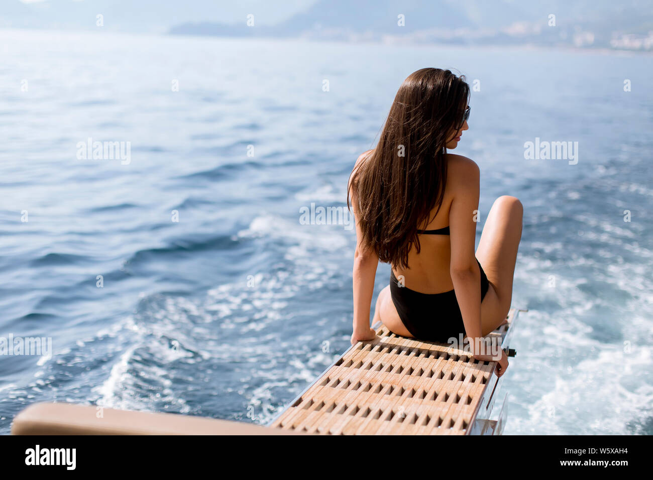 Pretty young woman with sunglasses relaxing on the yacht on sea at sunny day Stock Photo