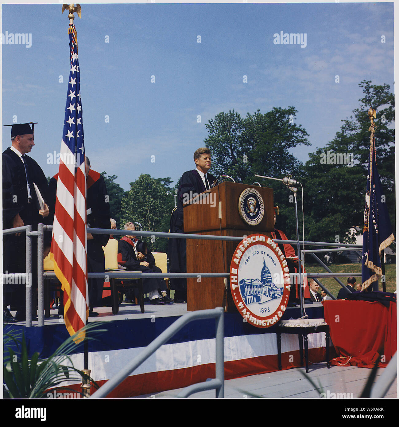 President addresses American University Commencement, recieves honorary degree. President Kennedy at Podium, speaker's platform guests. Washington, D.C., American University, John M. Reeves Athletic Field. Stock Photo