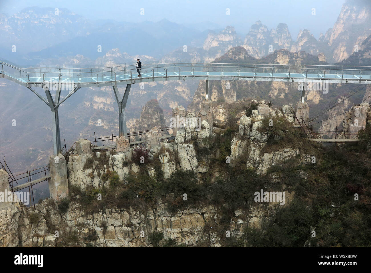 Tourists walk on the glass skywalk 'suspended' in the air along the cliff of Mount Langya in Baoding city, north China's Hebei province, 16 October 20 Stock Photo