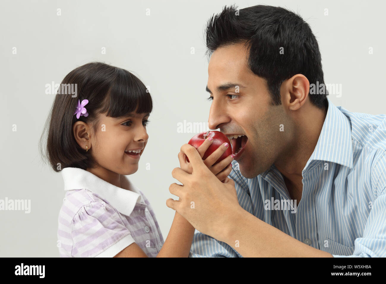 Girl feeding apple to her father Stock Photo Alamy